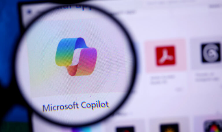 Microsoft Copilot logo viewed through a magnifying glass on a computer screen.