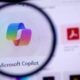 Microsoft Copilot logo viewed through a magnifying glass on a computer screen.